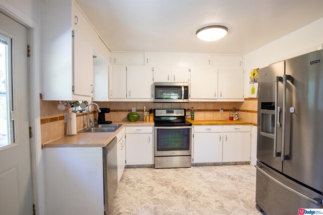 kitchen with stainless steel appliances, sink, a healthy amount of sunlight, backsplash, and light tile patterned floors