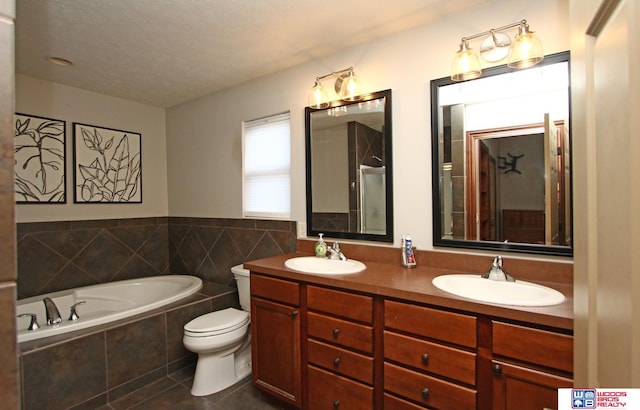 bathroom featuring tile patterned floors, double vanity, toilet, a textured ceiling, and a relaxing tiled tub