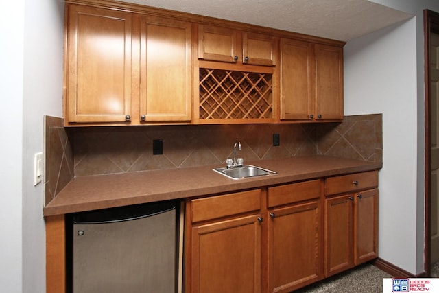 kitchen featuring carpet floors, sink, backsplash, and refrigerator