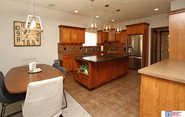 kitchen with decorative light fixtures, a center island, appliances with stainless steel finishes, light tile patterned floors, and backsplash