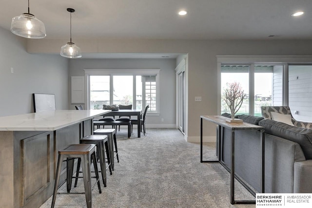 interior space with pendant lighting, light stone counters, light carpet, and a kitchen island