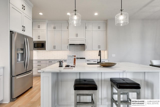 kitchen with sink, premium range hood, stainless steel appliances, light stone counters, and white cabinets