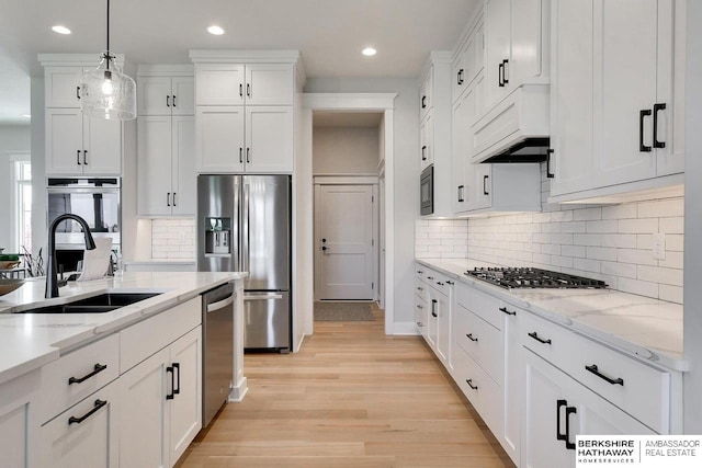 kitchen featuring sink, white cabinetry, decorative light fixtures, stainless steel appliances, and light stone countertops