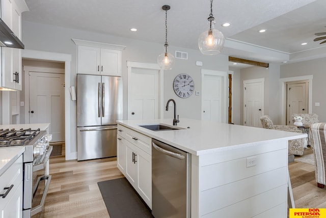 kitchen with white cabinetry, stainless steel appliances, light wood-type flooring, wall chimney exhaust hood, and sink