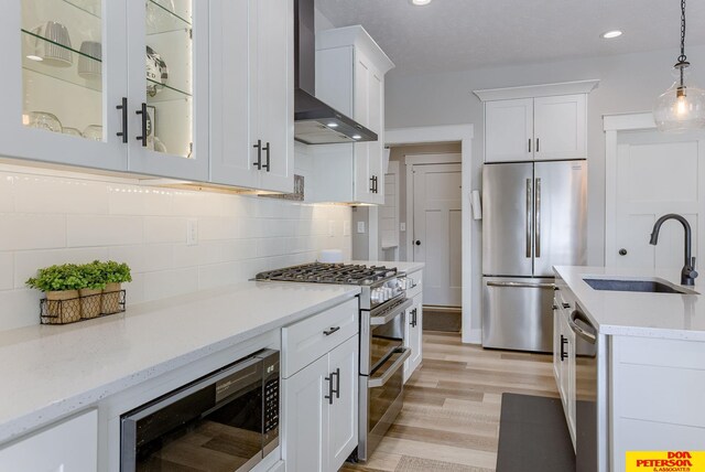 kitchen with white cabinetry, hanging light fixtures, decorative backsplash, an island with sink, and light hardwood / wood-style floors