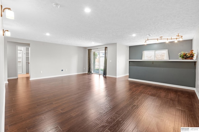 unfurnished living room with wood-type flooring, rail lighting, and a textured ceiling