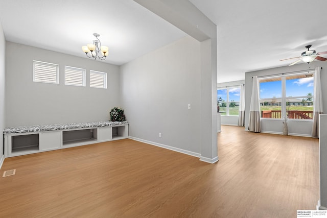 spare room with light wood-type flooring and ceiling fan with notable chandelier