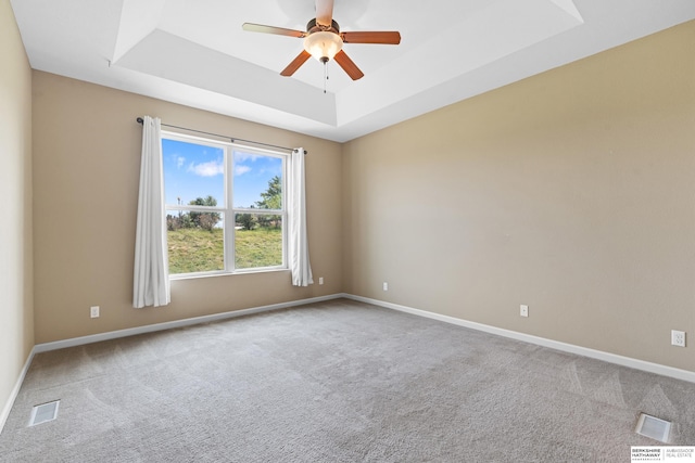 carpeted empty room featuring a raised ceiling and ceiling fan