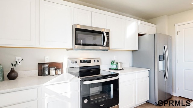 kitchen featuring wood-type flooring, appliances with stainless steel finishes, and white cabinets