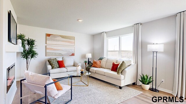 living room with a fireplace, a textured ceiling, and light hardwood / wood-style flooring