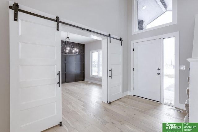 foyer entrance featuring light hardwood / wood-style floors, a barn door, and plenty of natural light