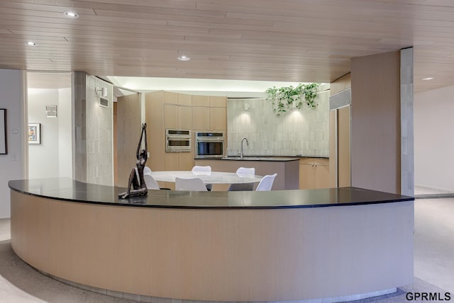 kitchen featuring wooden ceiling, sink, stainless steel oven, and a center island