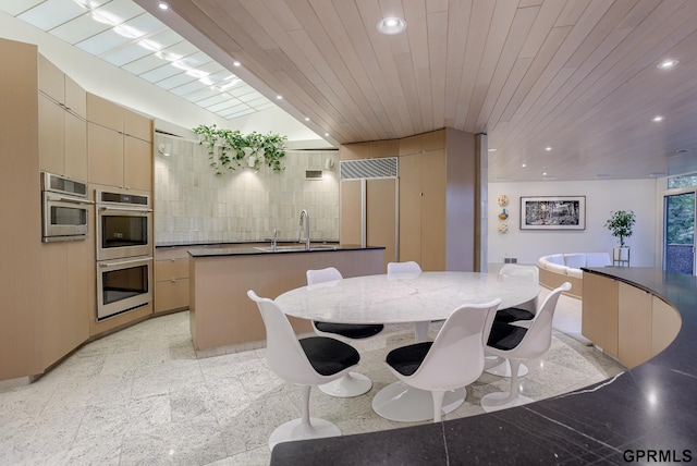 kitchen featuring wooden ceiling, stainless steel double oven, light tile patterned floors, sink, and a kitchen island