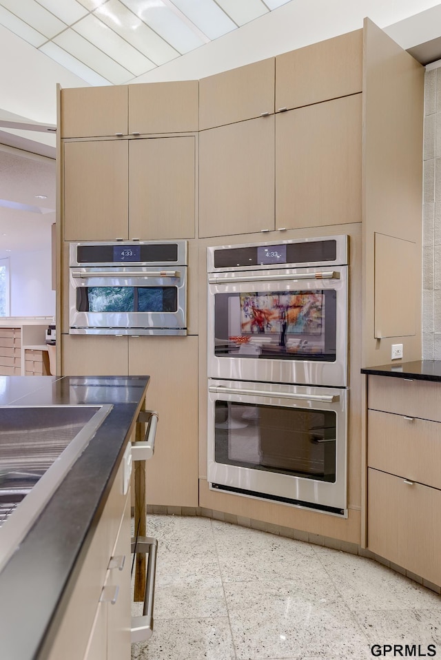 kitchen with stainless steel double oven and light brown cabinets