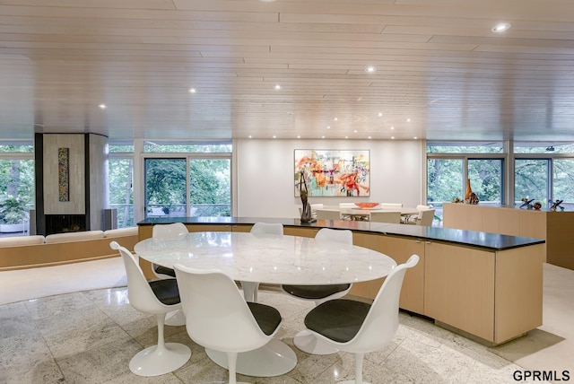 tiled dining space featuring wood ceiling, a wall of windows, and a healthy amount of sunlight