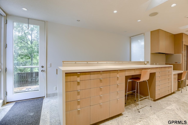 kitchen featuring built in desk, light brown cabinetry, a kitchen breakfast bar, and kitchen peninsula