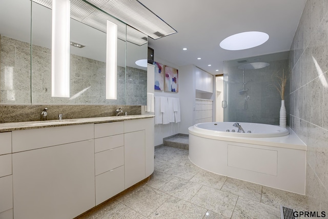 bathroom with tile walls, dual vanity, tile patterned floors, and independent shower and bath