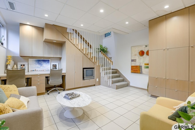 tiled living room featuring built in desk and a drop ceiling