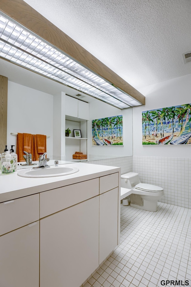 bathroom featuring vanity, a textured ceiling, toilet, and tile patterned flooring