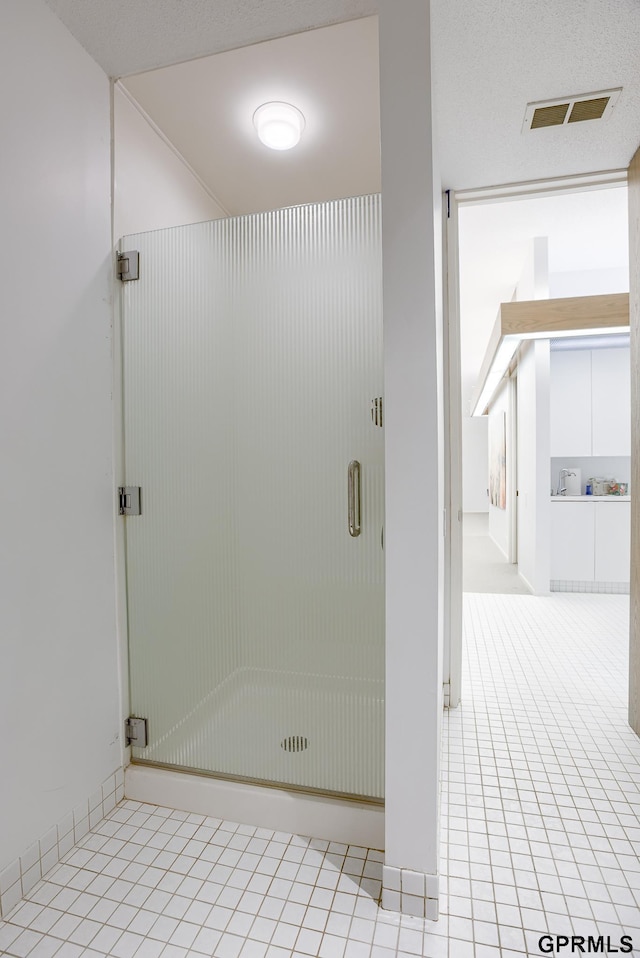 bathroom featuring a shower with shower door, a textured ceiling, and tile patterned flooring