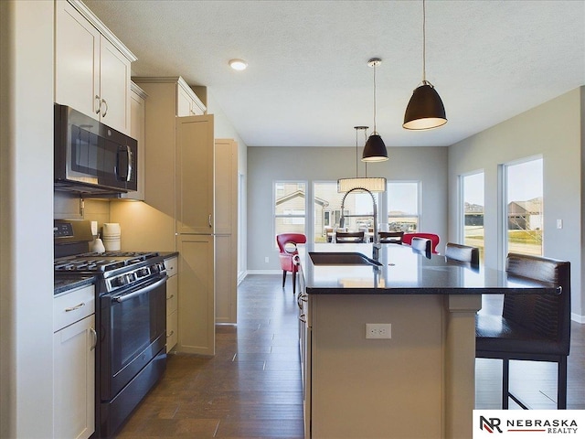 kitchen featuring a healthy amount of sunlight, dark hardwood / wood-style flooring, black gas range, and a center island with sink