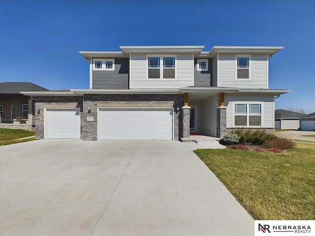 prairie-style home with concrete driveway, a front yard, stone siding, and an attached garage
