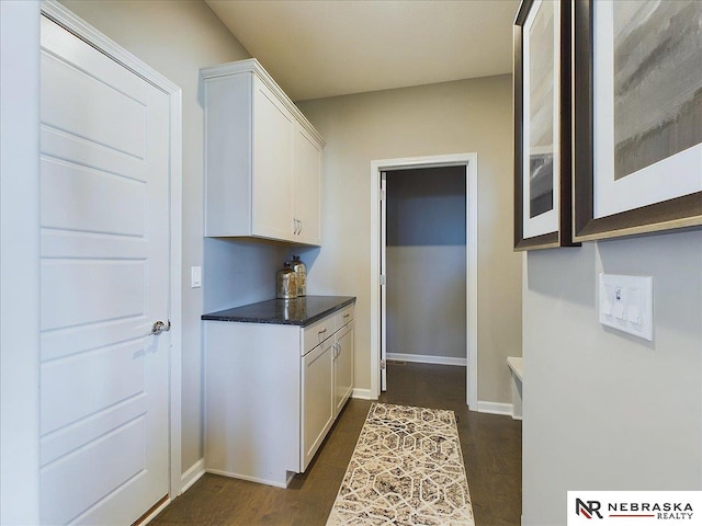 kitchen featuring white cabinets, dark countertops, baseboards, and dark wood finished floors