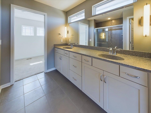 bathroom featuring tile patterned floors, double vanity, a sink, and a stall shower