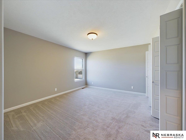 unfurnished room featuring baseboards, light carpet, and a textured ceiling