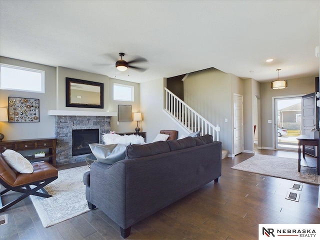 living room featuring baseboards, a ceiling fan, a fireplace, stairway, and dark wood-type flooring
