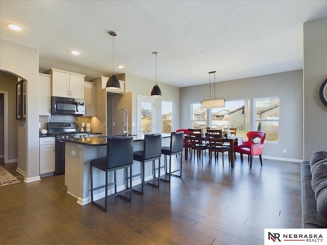 kitchen featuring range, white cabinets, dark hardwood / wood-style floors, a breakfast bar, and a textured ceiling