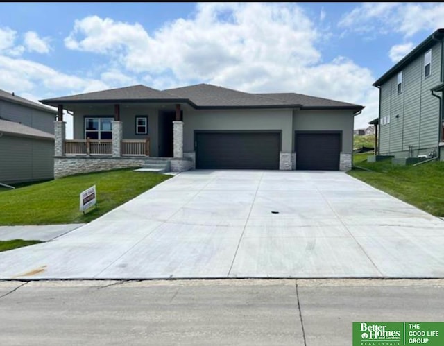 prairie-style home with a porch, a garage, and a front yard