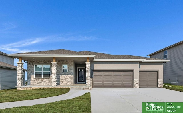 prairie-style house featuring an attached garage, driveway, a front yard, and stone siding