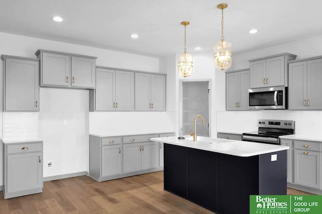 kitchen featuring a center island with sink, sink, gray cabinetry, and stainless steel appliances