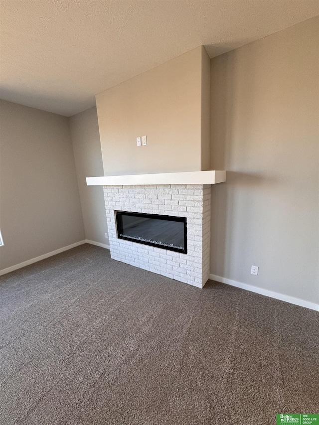 unfurnished living room with dark colored carpet, a textured ceiling, and a fireplace