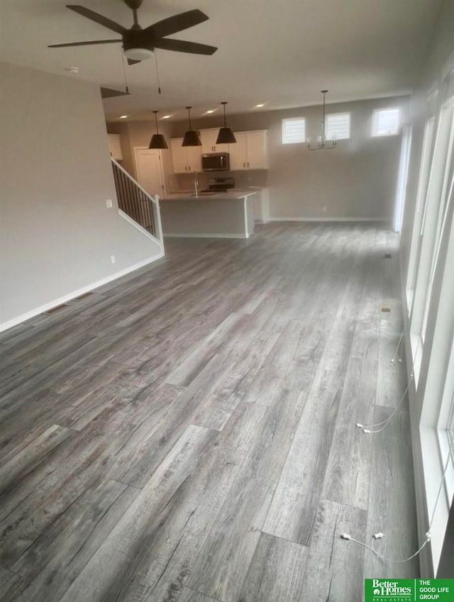 unfurnished living room with sink, hardwood / wood-style flooring, and ceiling fan with notable chandelier