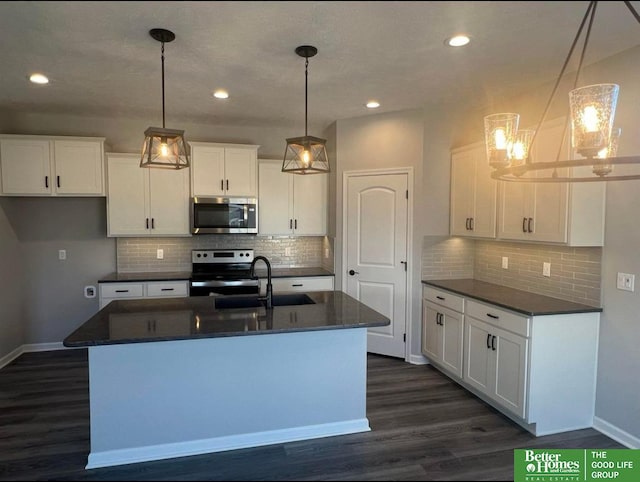 kitchen featuring decorative light fixtures, an island with sink, sink, appliances with stainless steel finishes, and white cabinets