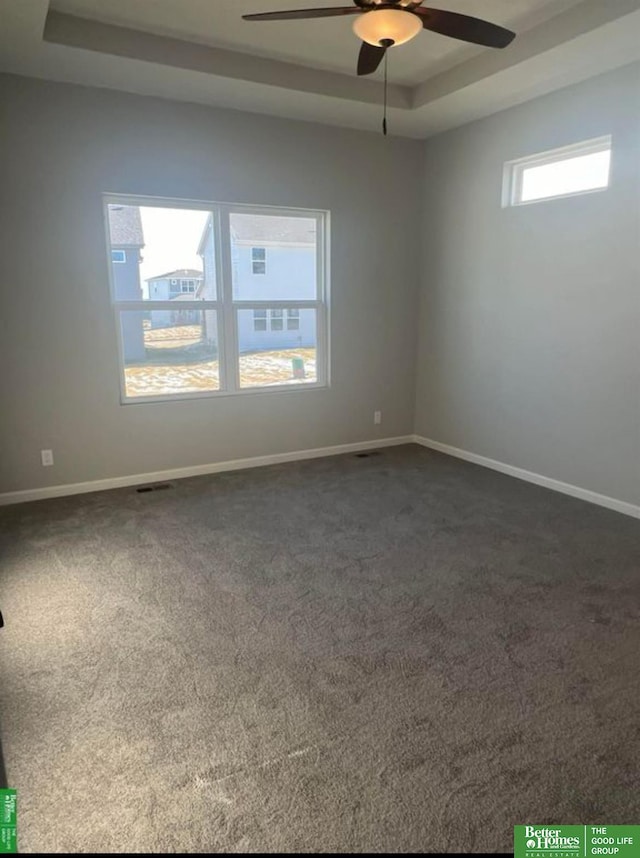 carpeted empty room featuring ceiling fan and a tray ceiling