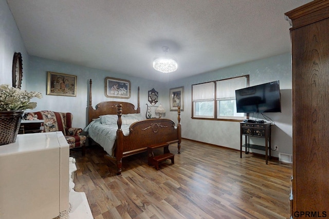 bedroom featuring a textured ceiling, a chandelier, and hardwood / wood-style floors