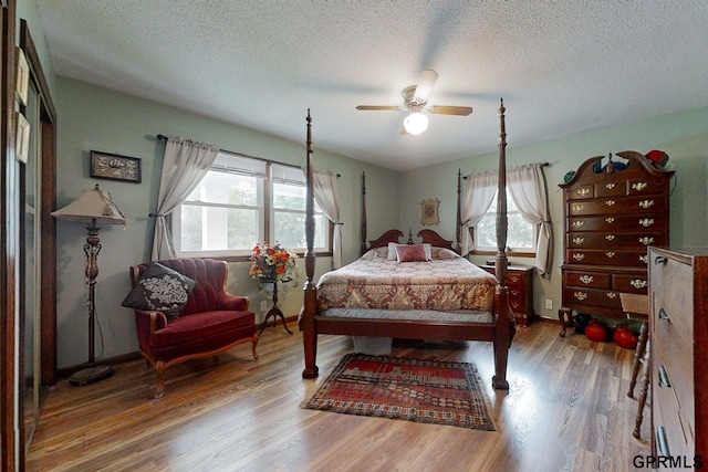 bedroom featuring ceiling fan, hardwood / wood-style flooring, and a textured ceiling