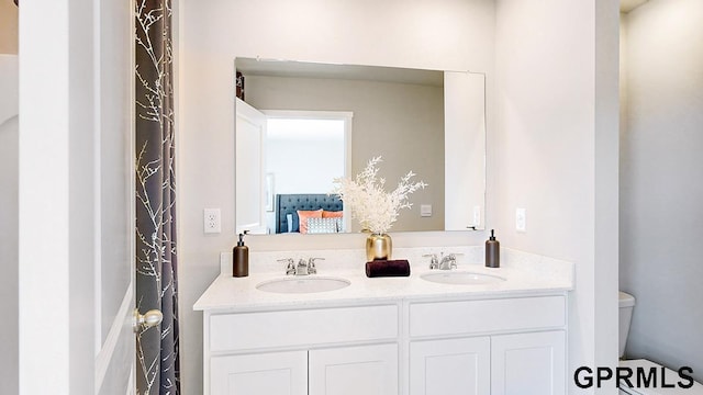 bathroom featuring dual vanity and toilet