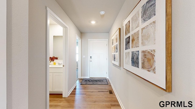 hallway with sink and light hardwood / wood-style floors