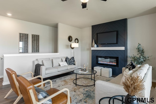 living room featuring hardwood / wood-style flooring, ceiling fan, and a fireplace