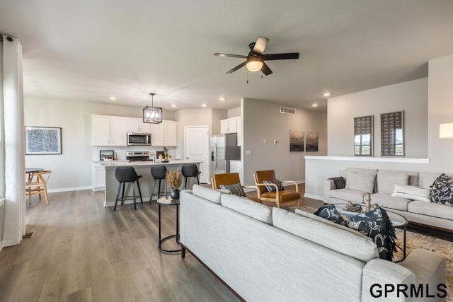 living room featuring ceiling fan and dark hardwood / wood-style floors