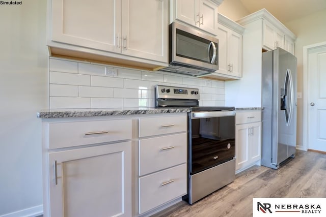 kitchen with light hardwood / wood-style flooring, appliances with stainless steel finishes, white cabinetry, light stone counters, and decorative backsplash