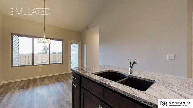 kitchen with sink, light stone counters, high vaulted ceiling, hanging light fixtures, and hardwood / wood-style flooring