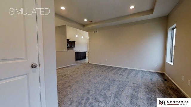 unfurnished living room with a tray ceiling and carpet floors