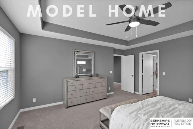 bedroom featuring light colored carpet, a raised ceiling, and ceiling fan