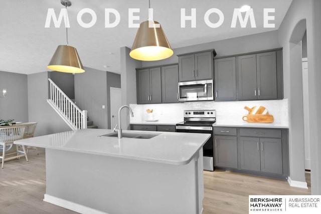 kitchen with a kitchen island with sink, sink, gray cabinetry, and appliances with stainless steel finishes