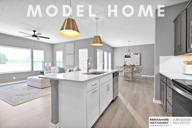 kitchen featuring pendant lighting, white cabinetry, sink, stainless steel dishwasher, and a center island with sink